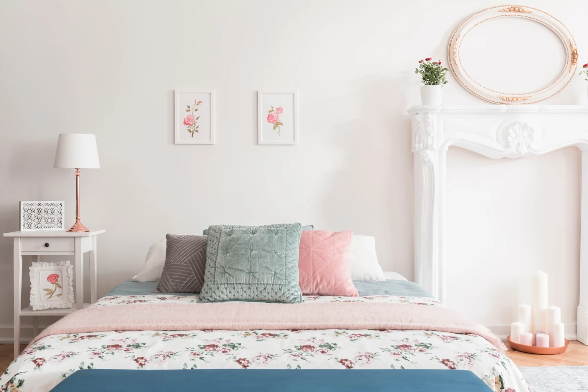 Łóżko z narzutą w kwiaty oraz z poduszkami w różnych kolorach.