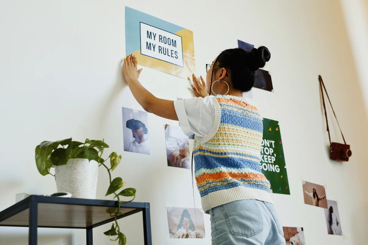 Dziewczynka zawiesza plakaty na ścianie w swoim pokoju.