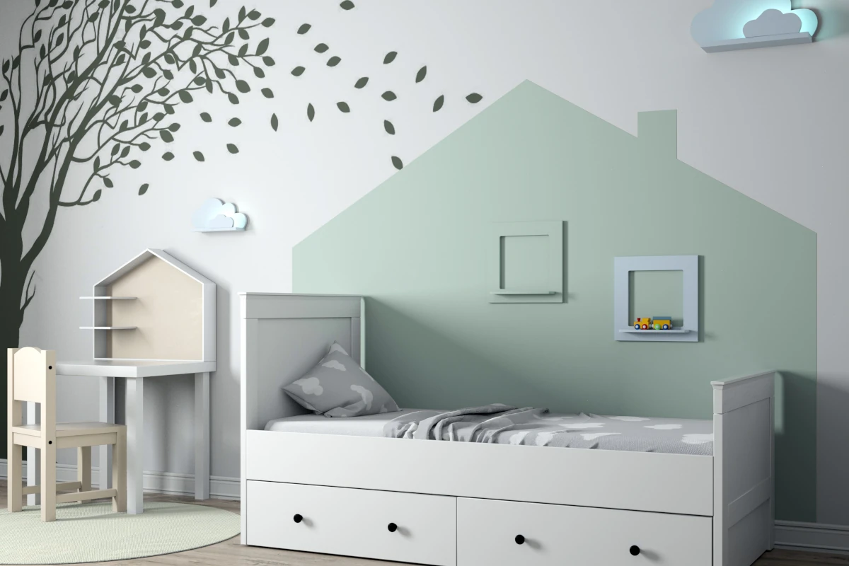 Namalowany domek na ścianie oraz drzewo. Łóżko oraz stolik do zabawy dla dziecka postawione przy ścianie.