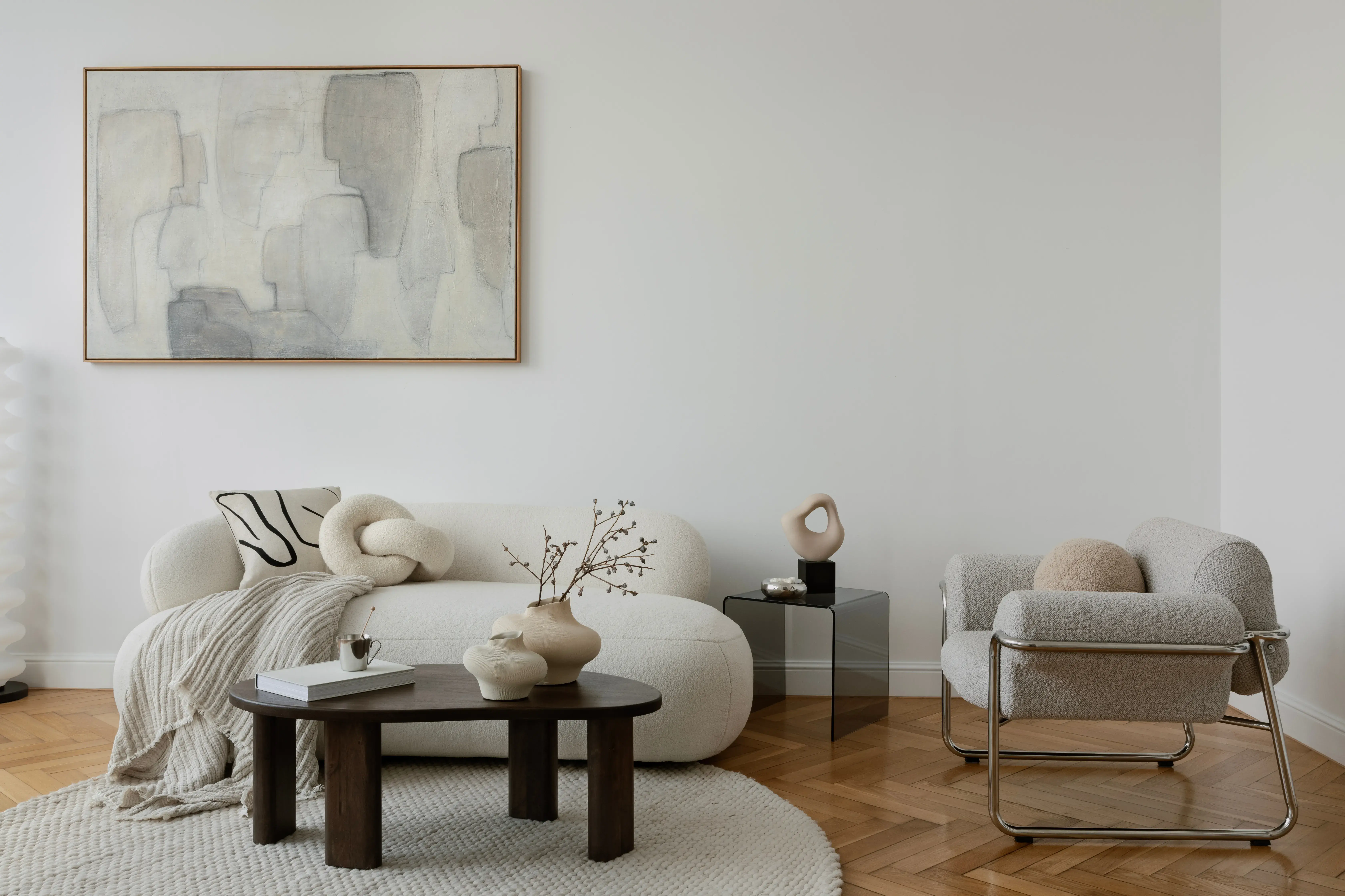 Salon w stylu nowoczesnym z szarymi ścianami, białą kanapą, czarnym stolikiem i krzesłem z szarym obiciem.